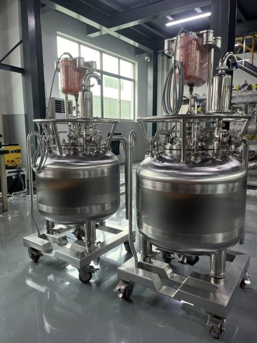 Two FUNDAMIX jacketed mixing vessels on mobile stainless steel skids in a workshop
